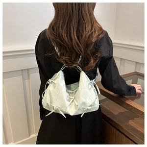 Detail of mint green shoulder bag with bow accents and soft textured finish