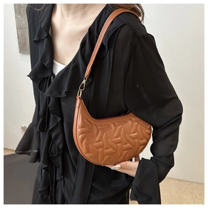 Detail of brown crescent bag showing geometric embossed texture and golden metal hardware