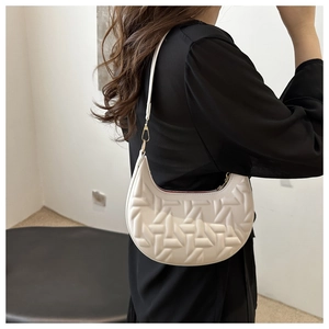 Close-up of white crescent shoulder bag featuring 3D geometric embossed pattern