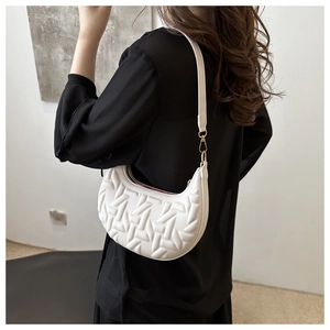 Detail view of white crescent hobo bag with geometric embossed texture on model's shoulder