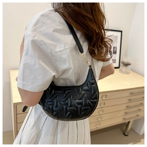 Detail of black crescent shoulder bag with 3D embossed geometric pattern and gold hardware