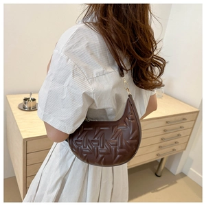 Detail of brown crescent bag with embossed geometric texture and gold metal hooks