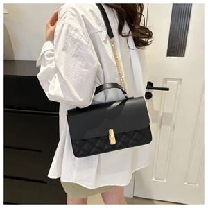 Detail of black crossbody bag with quilted texture and gold rectangular twist lock