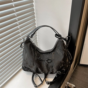 Minimalist black pleated shoulder bag with ribbon bow accents shown from a side angle