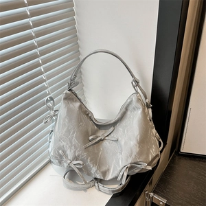 Silver metallic Hobo bag with bow details and wrinkled leather texture shown in lifestyle setting