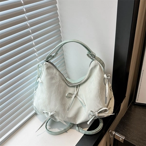Large mint green tote bag with bow details and pleated texture on window sill