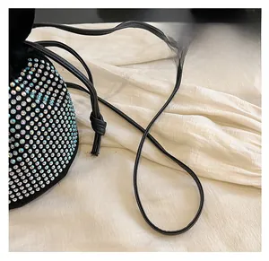 Detail of colorful rhinestones on a black drawstring bucket bag with a slim strap