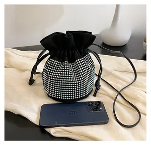 Detail of black drawstring bucket bag with sparkling silver rhinestones beside a phone