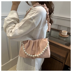 Detailed close-up of a pink pleated cloud bag with elegant faux pearl handle and shoulder strap