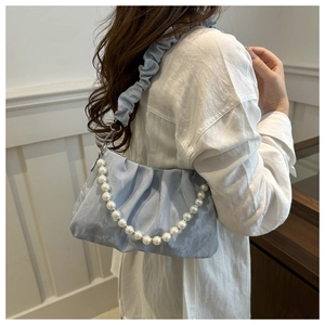 Detail of light blue cloud bag featuring large pearl chain and pleated fabric texture