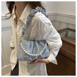 Close-up of light blue pleated handbag featuring a decorative white pearl bead chain