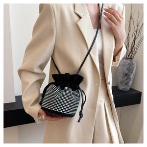 Detail of a black velvet bucket bag with sparkling rhinestones and a crossbody strap