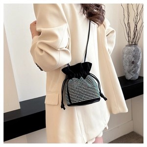 Detail of a black drawstring bucket bag with silver rhinestones on a beige suit