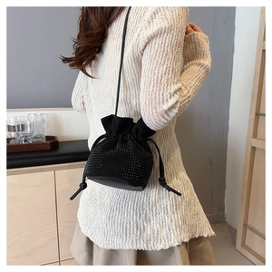Detail of black rhinestone drawstring bucket bag showing compact size and shiny texture