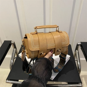 Vintage brown cylindrical handbag with embroidery strap on a modern chair