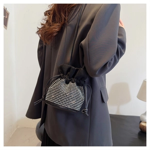 Detail of a black drawstring bucket bag with sparkling silver rhinestone dots and strap