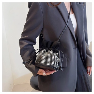 Detail of black rhinestone drawstring bucket bag with silver studs on model outfit