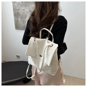 Rear view of a model wearing a white wrinkled leather backpack with silver metal handle