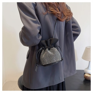 Close-up of black drawstring bucket bag with silver rhinestones on a blazer-clad model