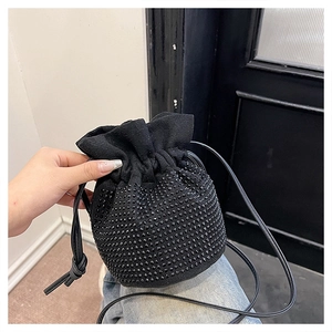 Detail of black drawstring bucket bag featuring shimmering rhinestones and soft suede texture