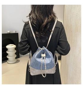 Detail of blue denim bucket bag with gray leather base shown on model's back