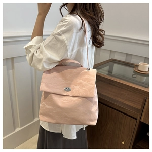 Close-up of pink pleated textured handbag with metallic twist-lock and shoulder strap