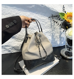Detail of canvas bucket bag showing metal chain drawstring and contrast paneling