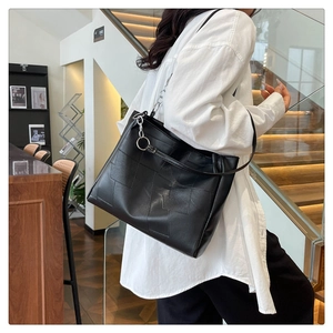 Detail of black geometric patchwork leather tote bag with stylish large silver metal ring