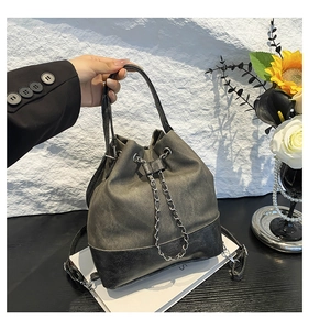 Close-up of drawstring bucket bag with contrast stitching and silver metal chain detail
