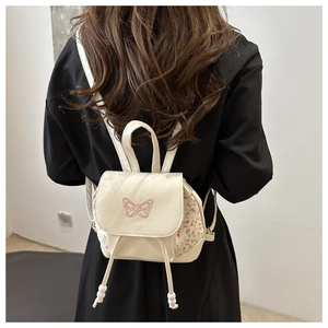 Detail of cream backpack with pink butterfly embroidery and floral side panels