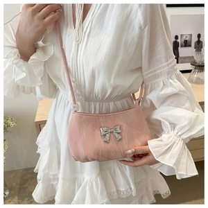 Detail of pink pleated shoulder bag with silver metal bow worn by a female model