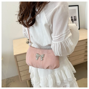 Detail of light pink shoulder bag with metallic bow and satin pleats on a model