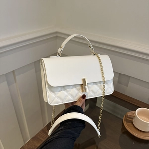 Elegant white quilted crossbody bag with gold hardware and chain strap held by hand