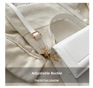 Close-up of golden adjustable buckle on a white leather shoulder bag with slim strap