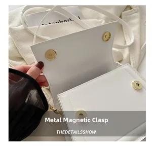 Detail view of four golden magnetic snaps on a white leather minimalist crossbody bag