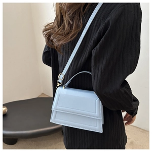 Detail of light blue crossbody bag with geometric texture and golden metal buckle