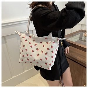Detailed close-up of corduroy tote bag with strawberry print and leather logo patch