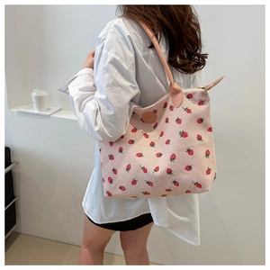 Detail of pink corduroy tote bag featuring strawberry prints and faux leather shoulder strap