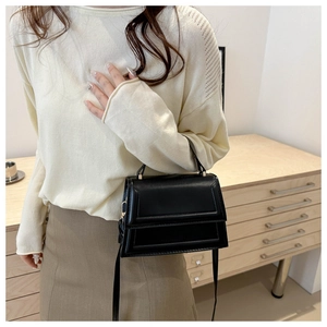 Detail of minimalist black PU leather crossbody bag with metal buckle and top handle