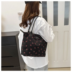 Detail of strawberry print corduroy tote bag showing the size and shoulder strap fit