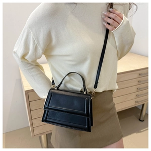 Detail of a chic black leather square handbag with top handle and crossbody strap