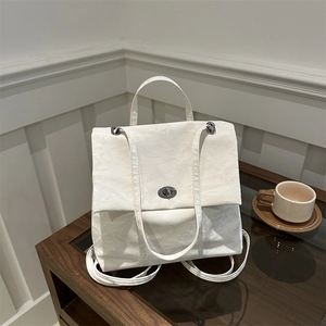 Chic beige backpack with pleated texture and metal lock on wooden table setting