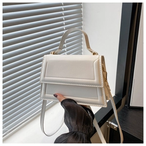 Close-up of white crossbody bag with geometric stitching and elegant top handle