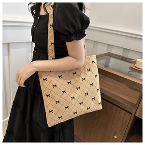 Detail of light brown corduroy tote bag with black quilted lattice and mini bow accents