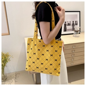 Vue détaillée du sac fourre-tout en velours côtelé jaune avec motifs de nœuds noirs