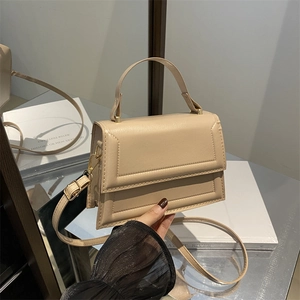 Minimalist beige crossbody bag with matte leather finish and golden hardware in studio