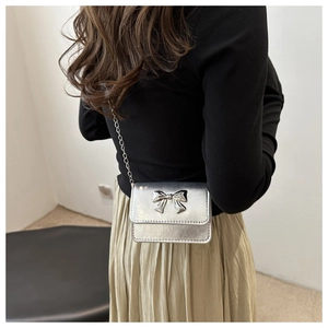 Detailed back view of a silver metallic crossbody bag with chain strap and bow