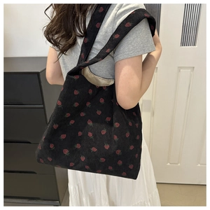 Detail of strawberry print corduroy tote bag showing textured fabric and casual fit