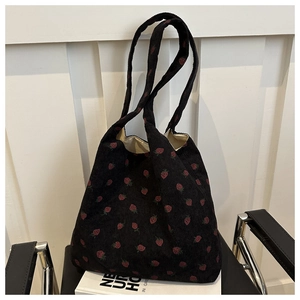 Detail of black corduroy tote bag with red strawberry print and soft inner lining