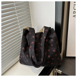 Detail of strawberry print on black corduroy tote bag with dual shoulder straps